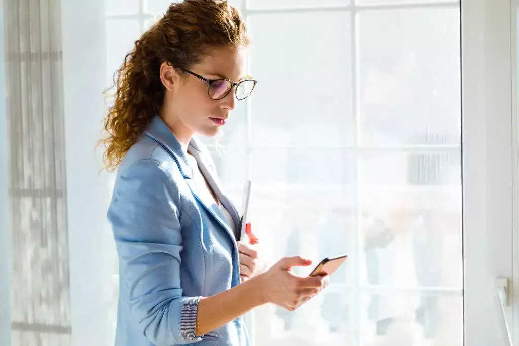 Businesswoman using smartphone near window