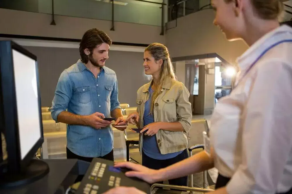 Couple checking in at airport kiosk with agent.