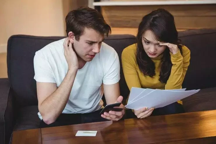 Worried couple reviewing financial documents and phone, considering AFSL requirements for superannuation trustee services.