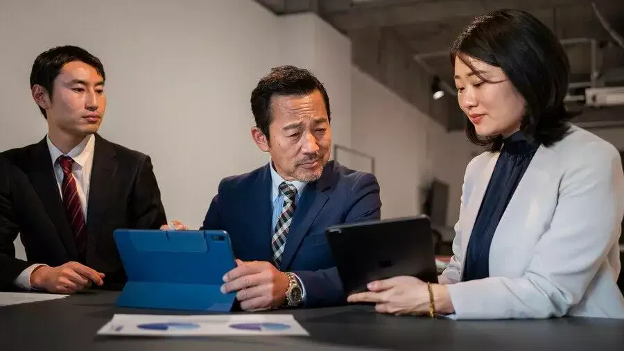 Three businesspeople review documents for an AFSL licence application, ensuring Australian financial services compliance.
