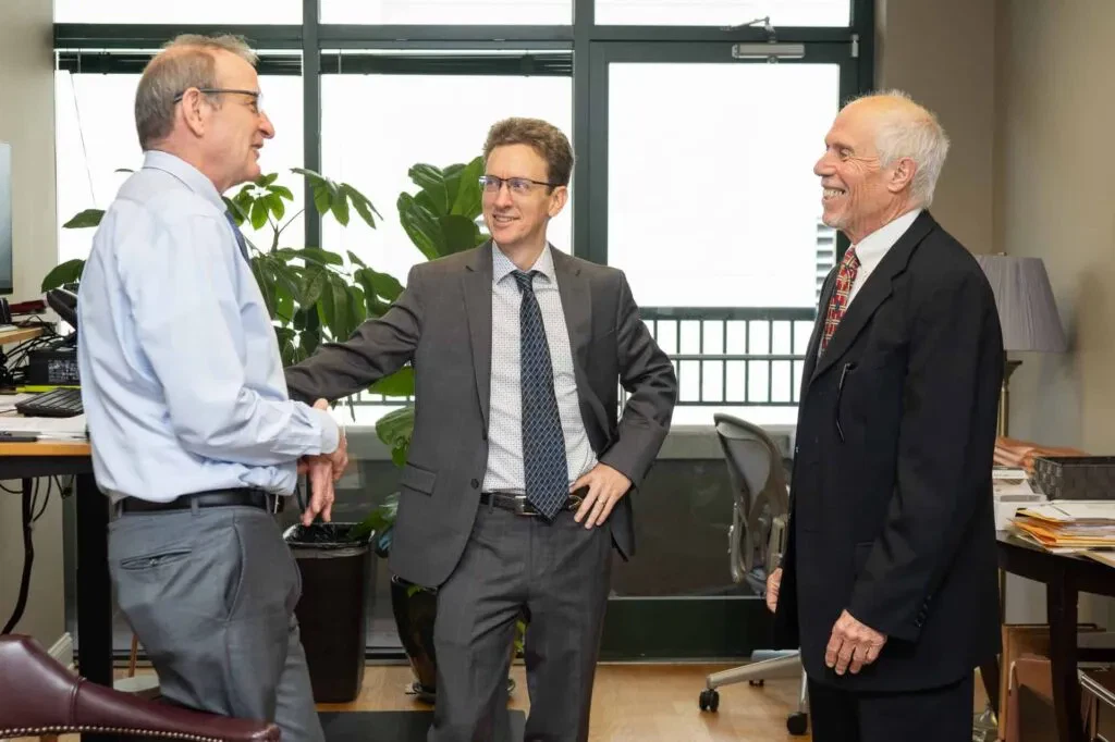 Three businessmen in suits discussing business. COI lender compliance.