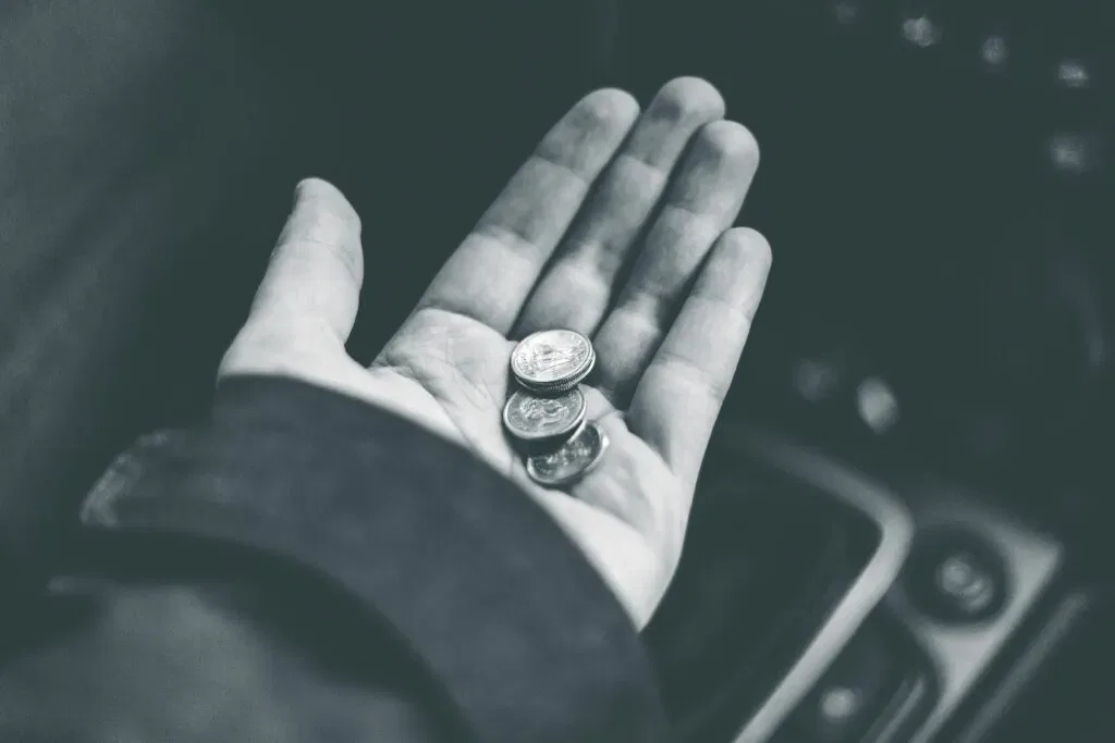Black and white image of a hand holding a few coins, symbolizing financial implications of CSLR levy explained.