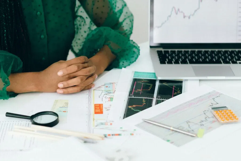Person reviews charts, graphs, and documents on a desk with a laptop, related to AFSL risk management requirements.