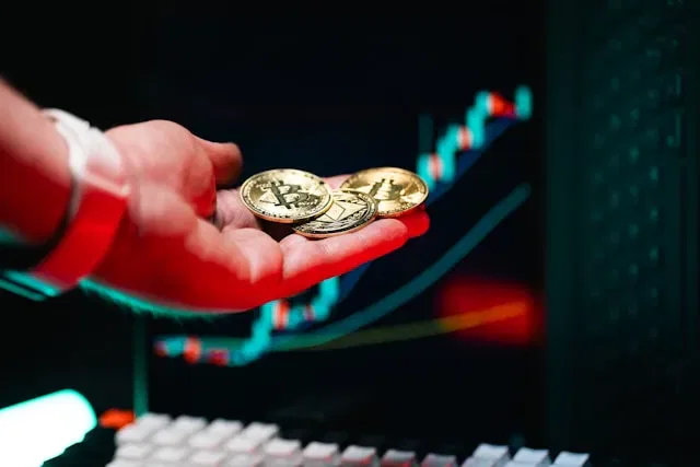 Hand holding Bitcoin and crypto coins in front of a stock chart.