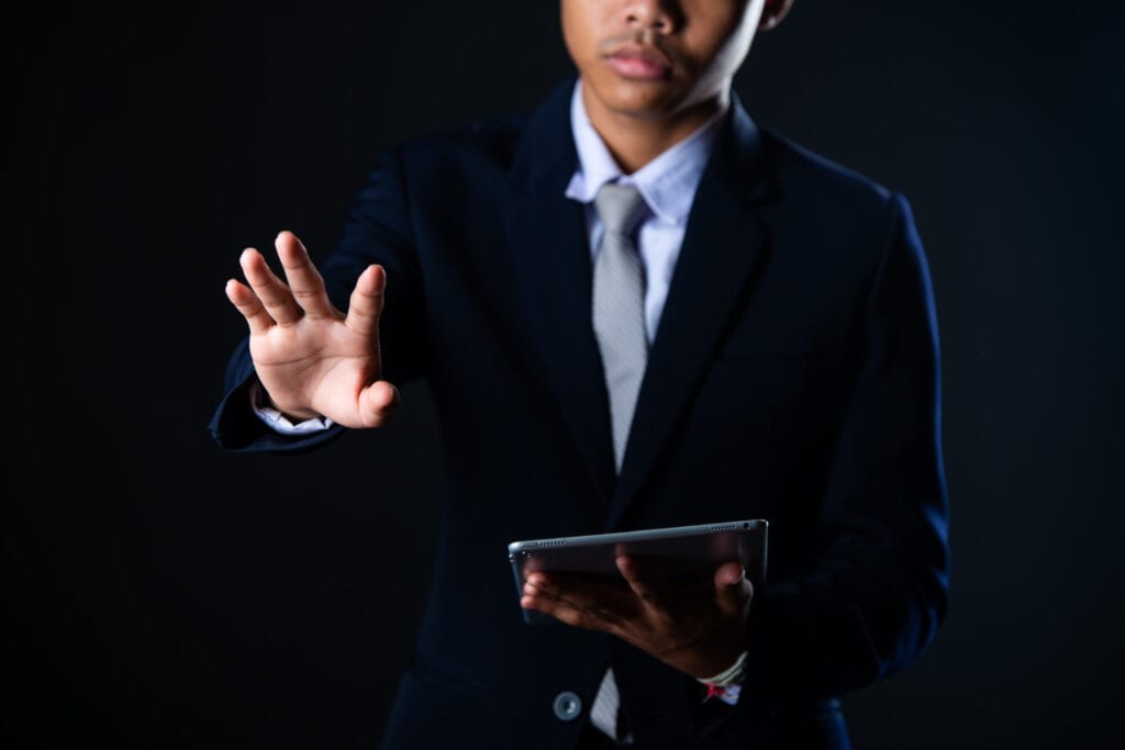 Businessman in suit using a tablet, gesturing towards a virtual screen. Private credit concept.