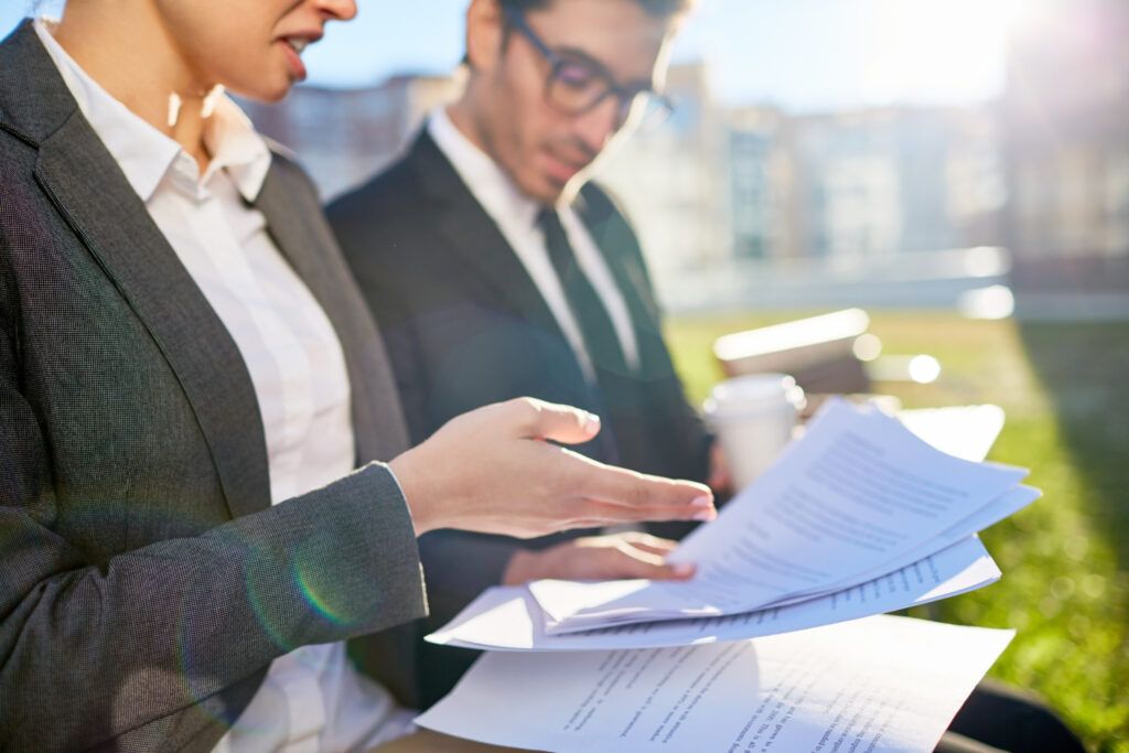 Business professionals reviewing documents outdoors, possibly discussing APRA CPS 230 operational risk compliance.