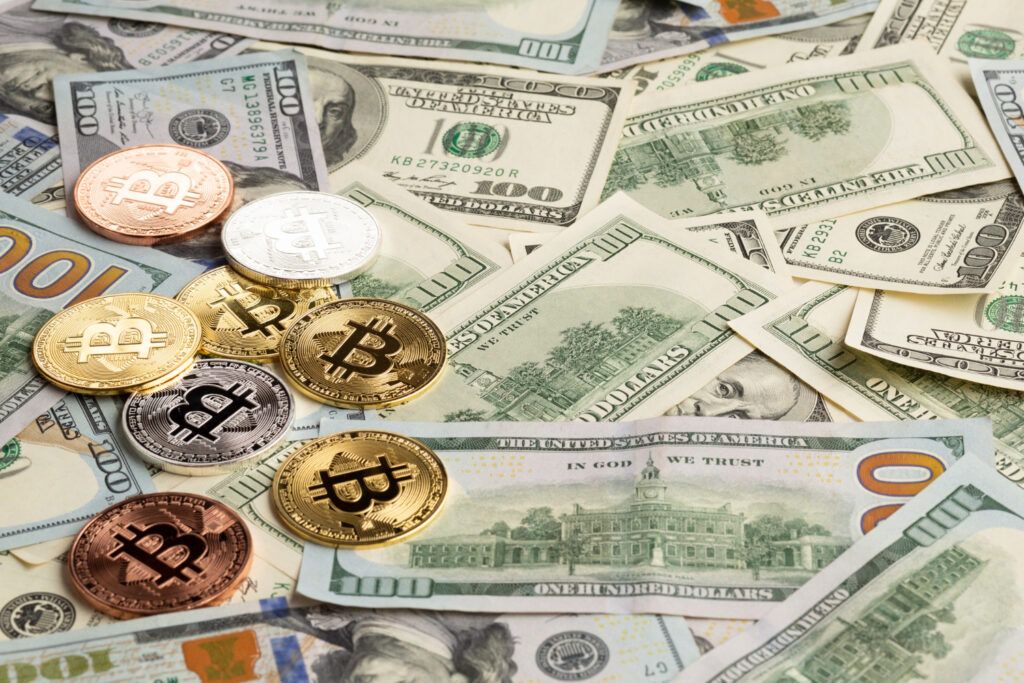 Bitcoin coins scattered on US Dollar bills. Crypto and traditional currency.