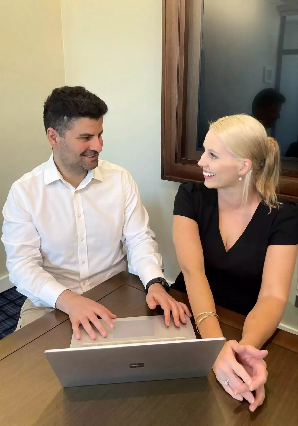 Two business professionals collaborate on a laptop, discussing a project.