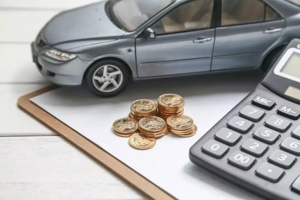 Toy car, coins, and calculator on a clipboard; illustrating financial planning.