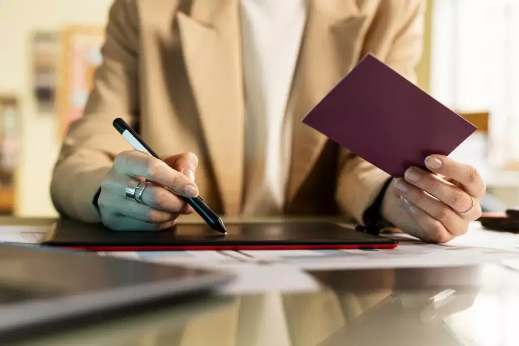 Woman using a stylus on a graphics tablet, reviewing a document. AFCA membership.