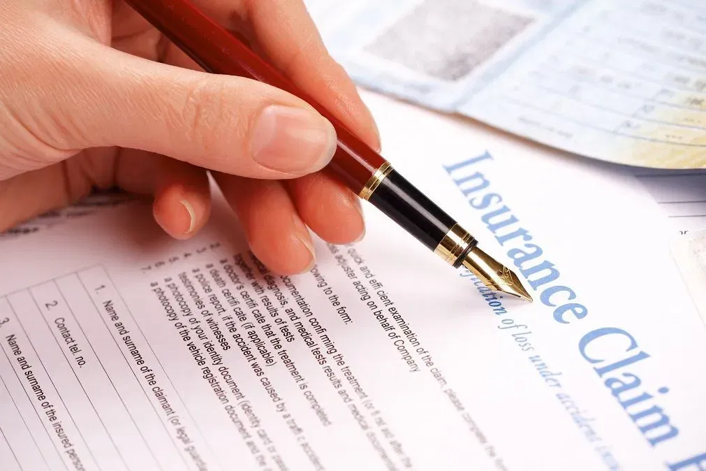 Person filling out an insurance claim form with a fountain pen. 