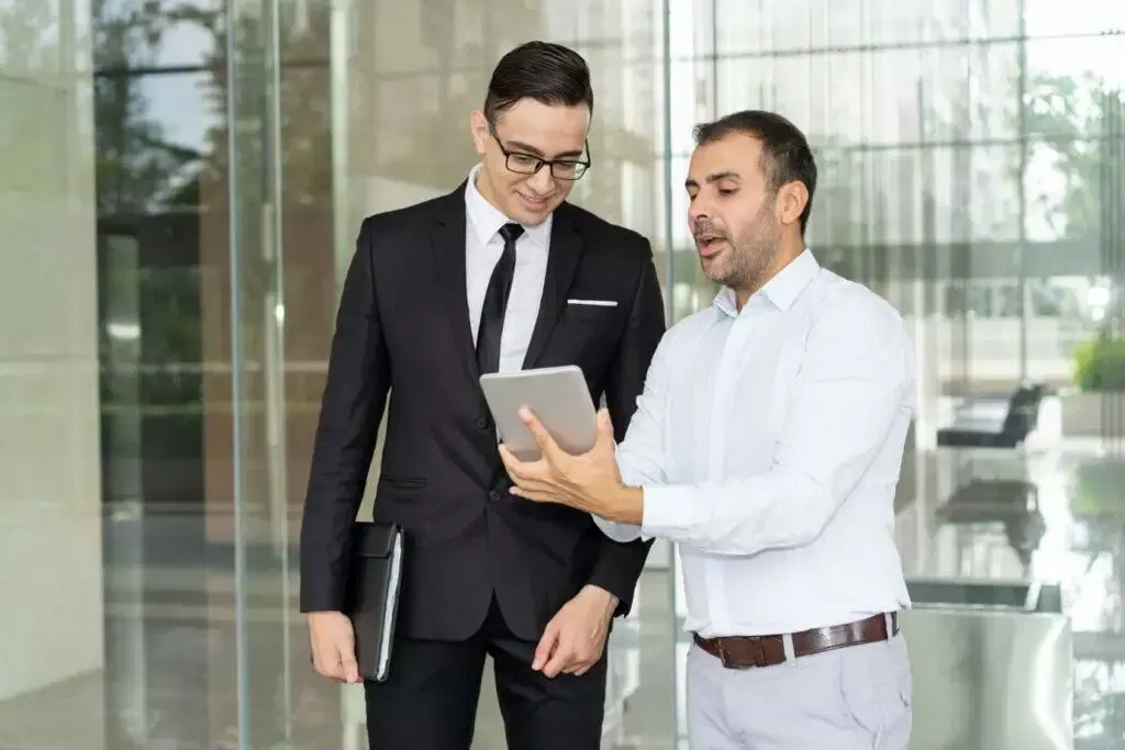 Two Australian financial services licensees review a tablet displaying financial data.