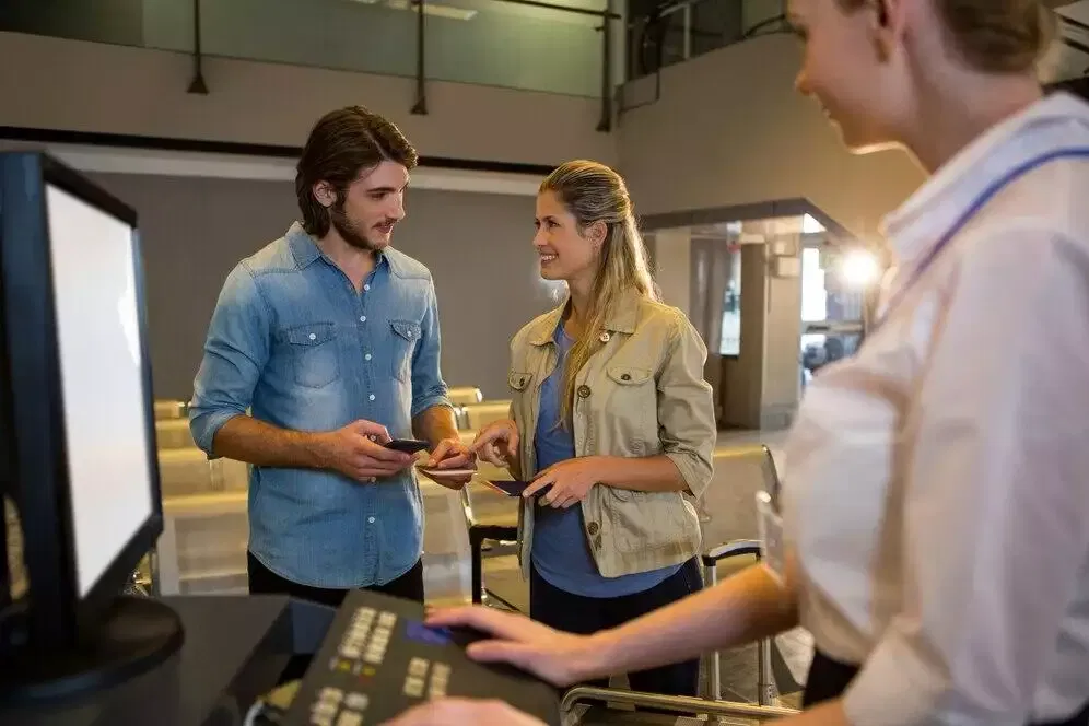 Couple checking in at airport kiosk with agent.