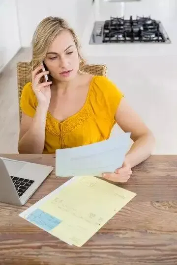 Woman reviewing documents while on a phone call, possibly related to an Australian credit licence application.