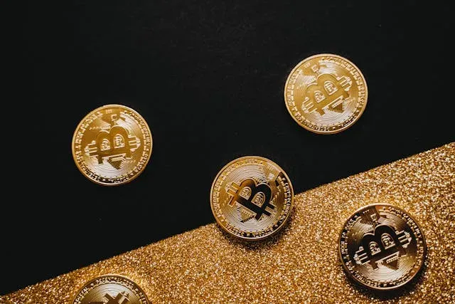 Gold Bitcoin coins scattered on a black and gold glitter background.