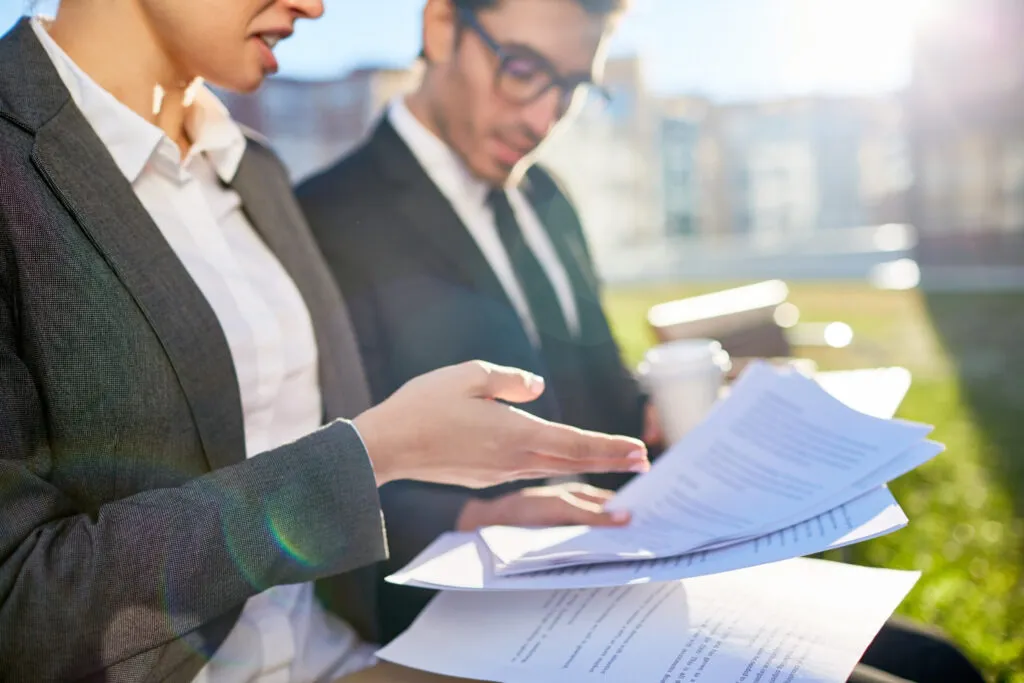 Business professionals reviewing documents outdoors, possibly discussing APRA CPS 230 operational risk compliance.