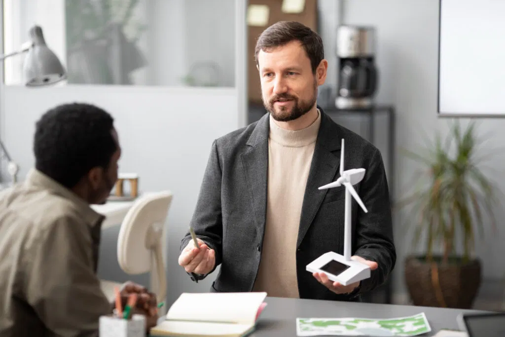 Businessmen discussing carbon credits with a wind turbine model on the desk, related to AFS Licence.